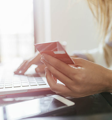 Woman with 1 hand holding credit card and the other on laptop