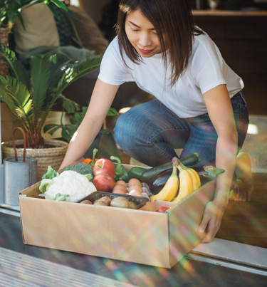 Woman picking up box of groceries