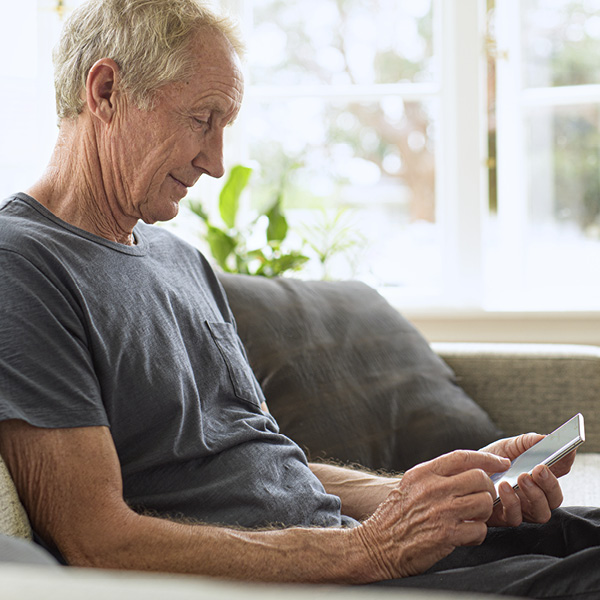 Man on couch looking down at mobile screen
