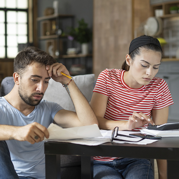 Man and woman in lounge looking concerned at papers