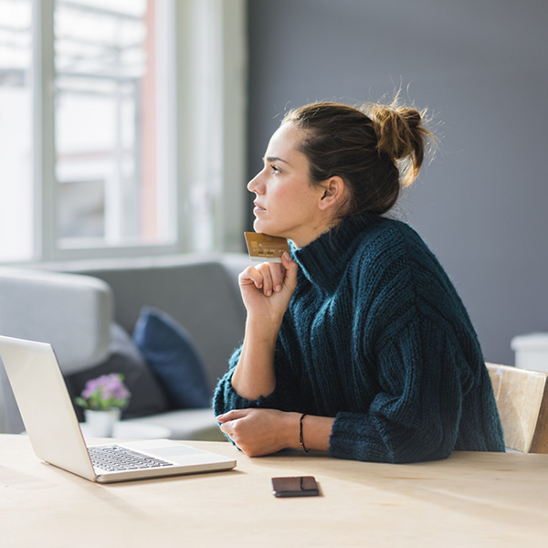 Woman in-front of laptop holding credit card