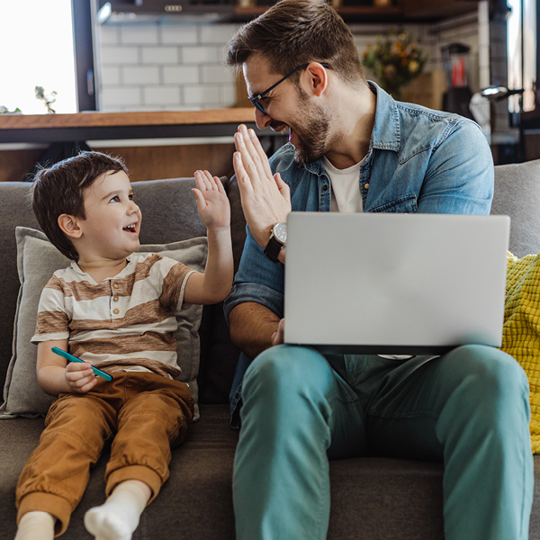 man with laptop and son high five 