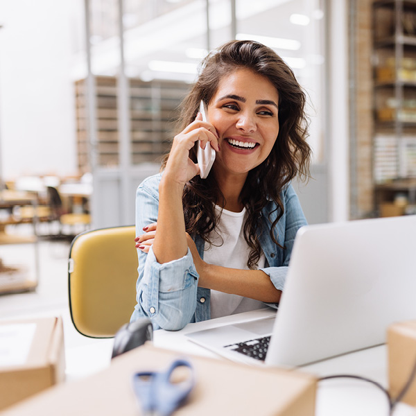 woman talking on phone, sitting in front of a computer