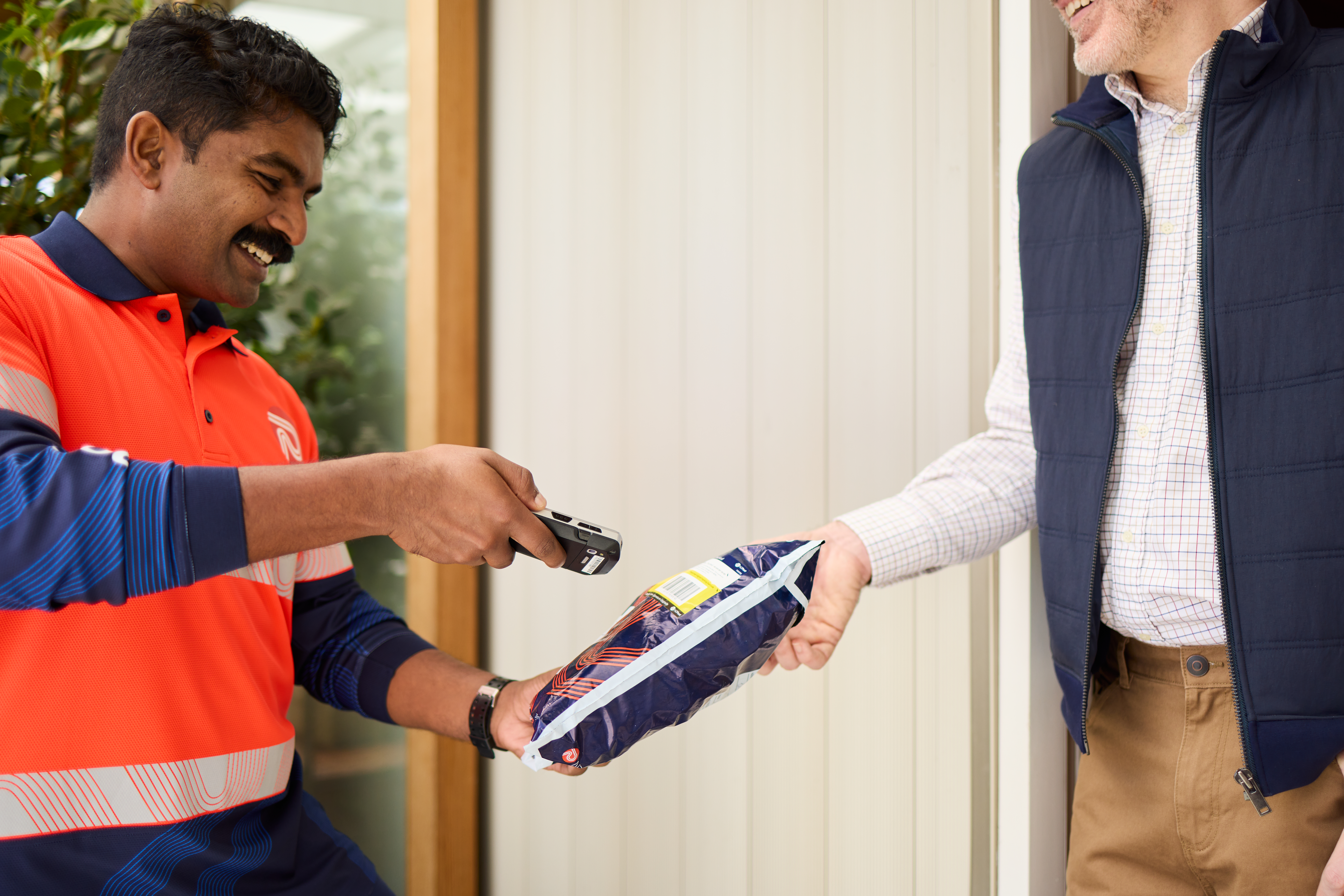 Parcel being scanned on delivery by a man in a high vis shirt