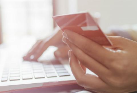 Woman with 1 hand holding credit card and the other on laptop