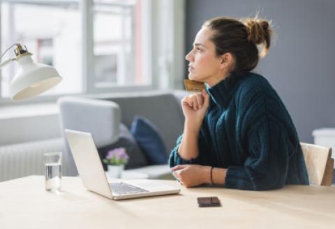 Woman sitting next to a laptop with credit card in hand