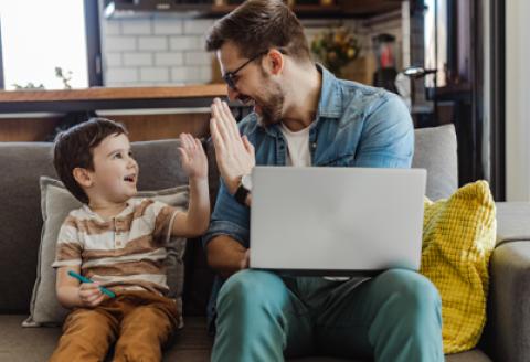 man with laptop and son high five