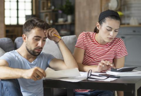 Man and woman in lounge looking concerned at papers