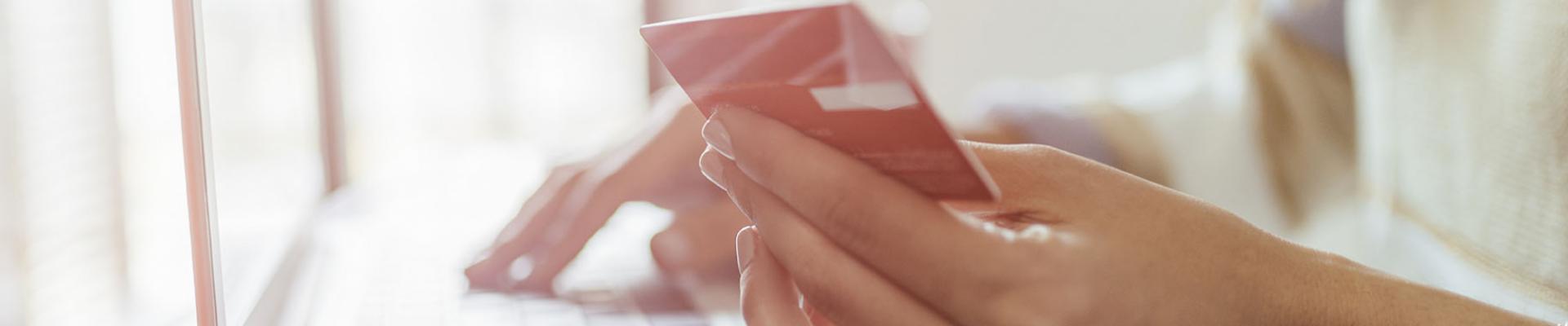 Woman with 1 hand holding credit card and the other on laptop