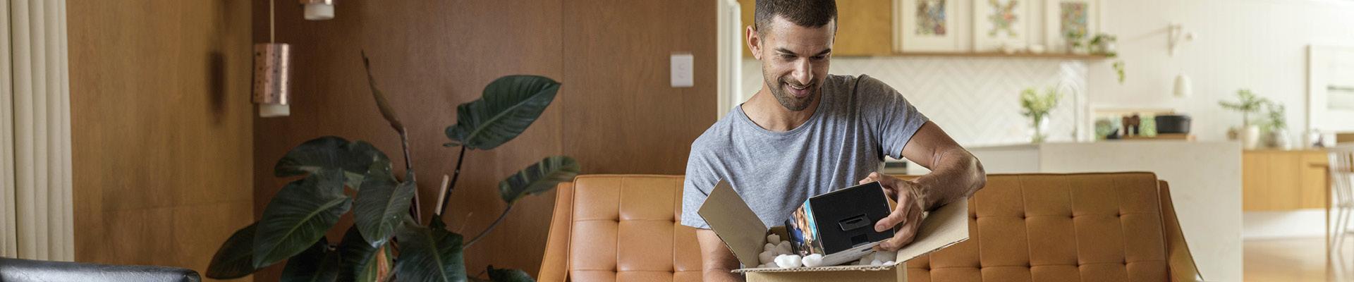 Man sitting on couch opening box
