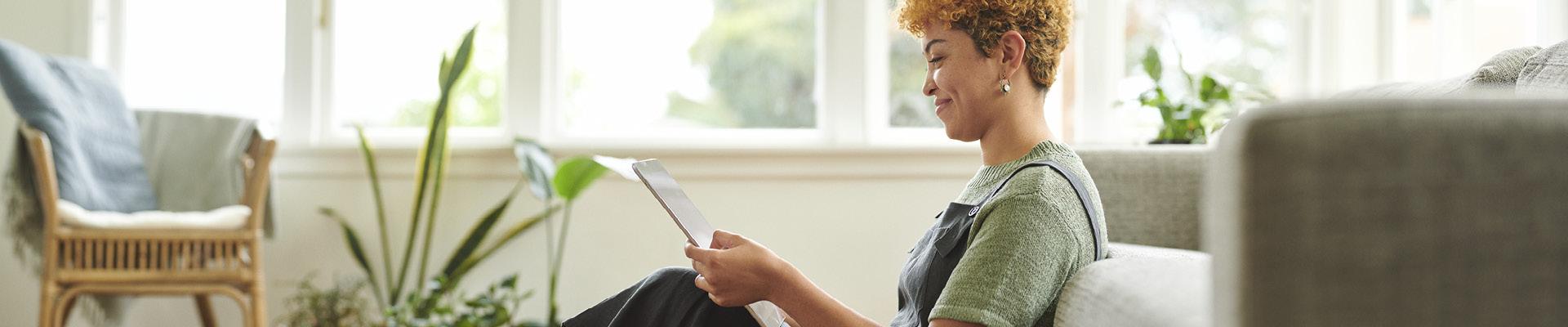 Women leaning on couch looking at tablet device