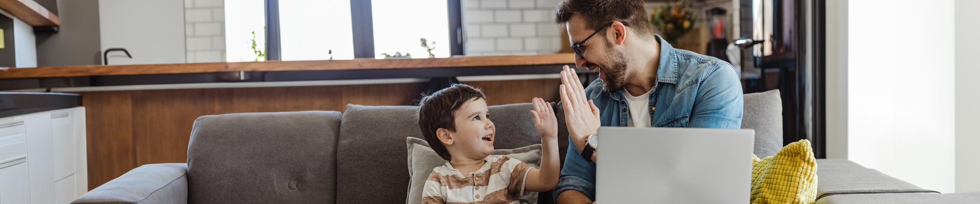 man with laptop and son high five 