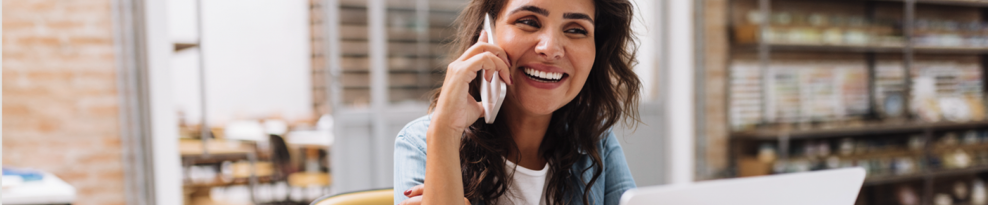 woman talking on phone, sitting in front of a computer