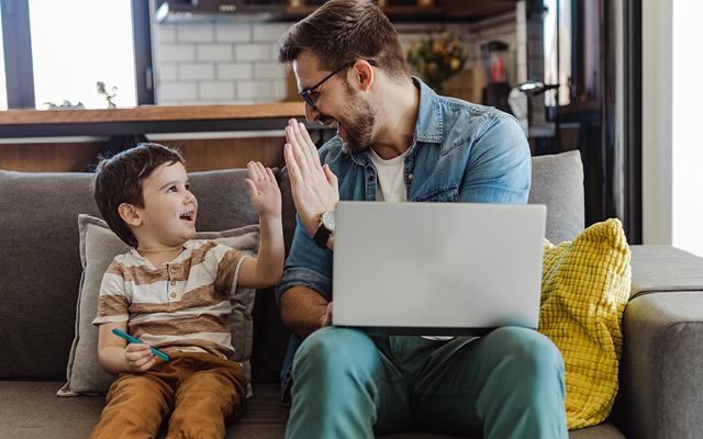 man with laptop and son high five